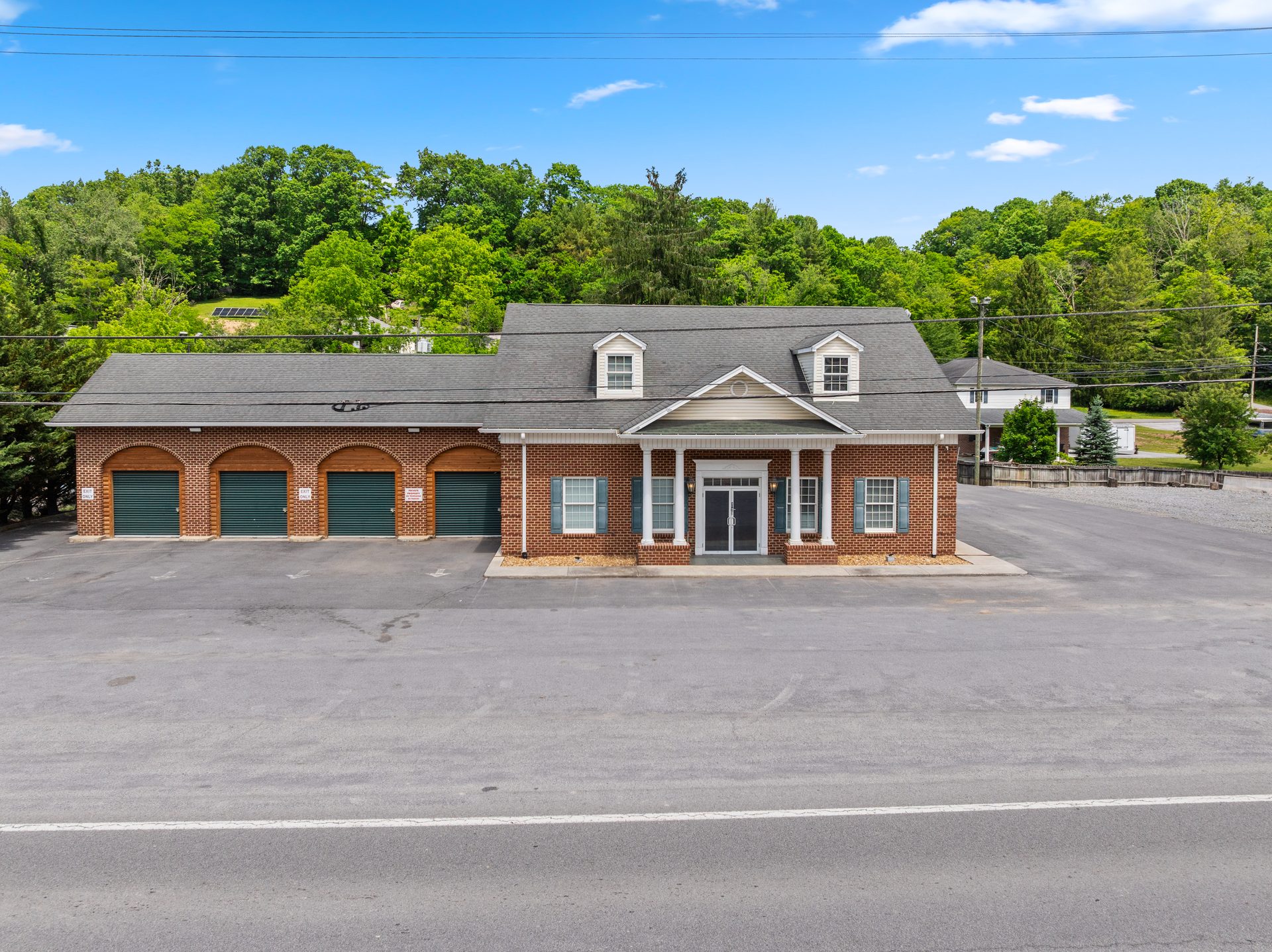 Exterior drone view of The Old Bank Lodge — brick building with columned entrance and green garage bays