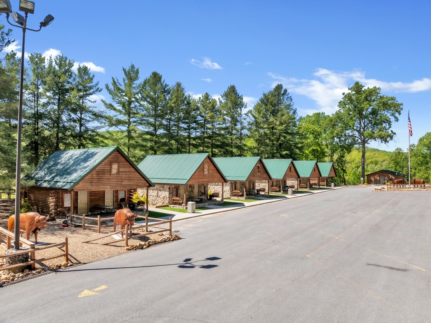 Row of stone and log cabins with green metal roofs at Buffalo Trail Resort