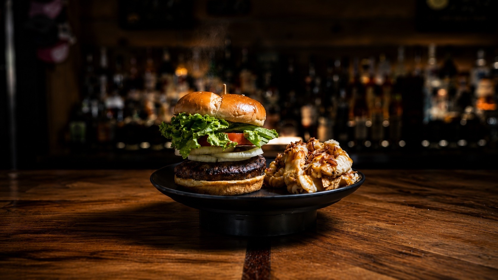 Build-your-own cheeseburger with lettuce, tomato and onion on a brioche bun beside bacon mac and cheese