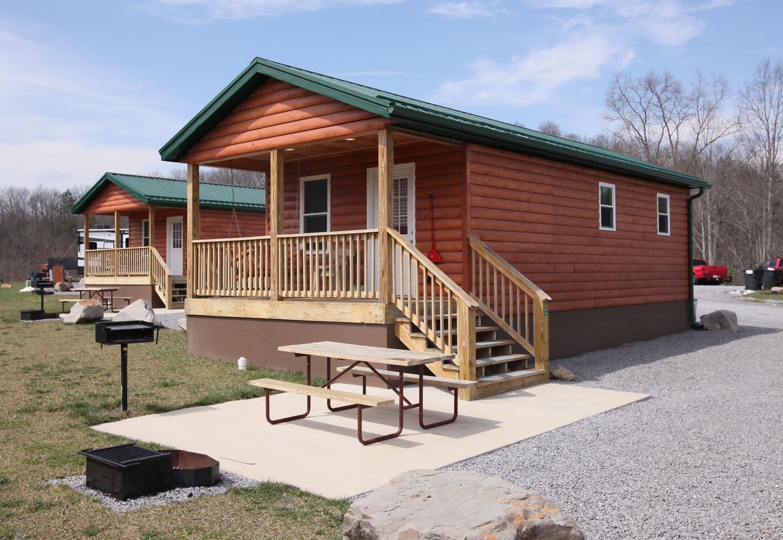 Deluxe Cabin 2 — Deluxe Cabin exterior with covered porch and picnic table